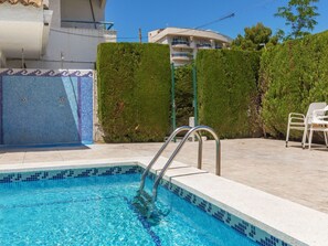 A swimming pool with a tiled edge, a metal ladder, and a white chair. - Marc Miami by Interhome (Miami Platja)