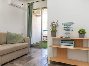 A living room with a sofa, a potted plant, a signboard, and a wooden shelf. - Marc Miami by Interhome (Miami Platja)