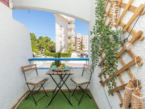 Un balcó amb taula i cadires, una planta penjant i una estructura de latic treballat.