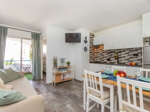 Un espai vital compacte amb una cuineta, zona de dinar i sofà.