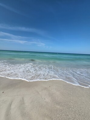 A beach with clear water and a sandy shore. - Make Beach Memories Luxury AMI House Steps to Sand (Holmes Beach)