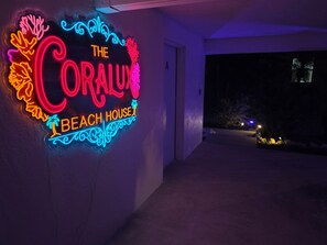 A neon sign with the text 'The Coral Reef Beach House' against a dark background. - Make Beach Memories Luxury AMI House Steps to Sand (Holmes Beach)