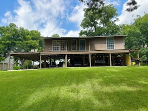 A two-story house with a covered patio area. - Lakehouse 3BR Retreat –Kayaks, Paddleboards, Floating Dock, PingPong, Volleyball (McQueeney)