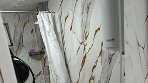 Une salle de bain avec un lavabo blanc, un miroir et un mur décoré d’un motif marbré.
