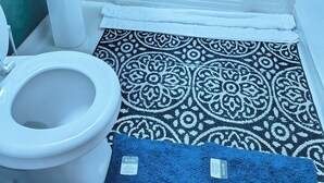Een badkamer met een wit wastafelmeubel, een toilet en een bad.