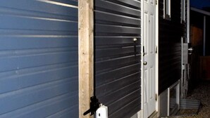 A building with a metal exterior, a wooden post, and a concrete pathway leading to a door. - Private 2BR Suite | Kitchen & Laundry (Saskatoon)