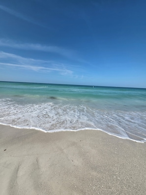 A beach with clear water and a sandy shore. - Make Beach Memories - Luxury AMI 2BR Beach House (Holmes Beach)