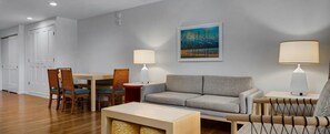 Ein modernes Wohnzimmer mit einem grauen Sofa, Holzstühlen, einem kleinen Tisch und zwei Lampen.