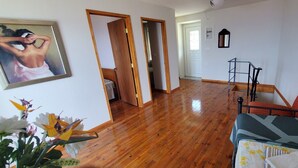A room with wooden flooring, a bed with patterned bedding, a chair, a small table, and a picture on the wall. - Gorgeous 2-bedroom cottage with AC in charming Glossa (Glossa)