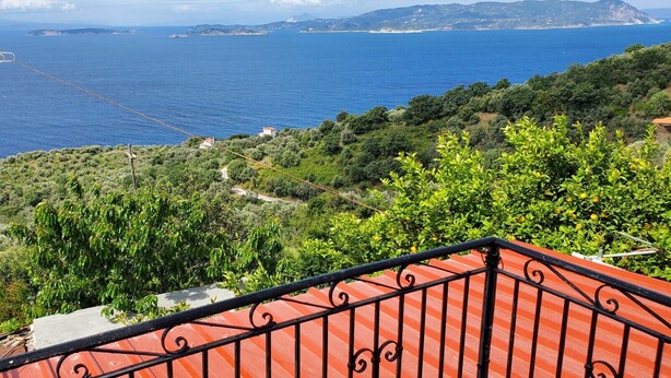 A balcony with a red railing overlooking a coastal landscape with greenery and a view of the sea. - Gorgeous 2-bedroom cottage with AC in charming Glossa (Glossa)