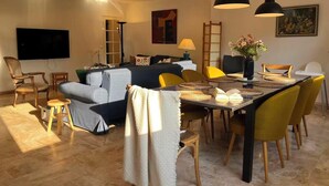 Ein modernes Wohnzimmer mit einer Couch, einem Esstisch, Stühlen und einem Flachbildfernseher.