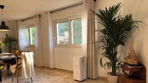 Ein geräumiges Zimmer mit Essbereich, großen Fenstern, einer Heizung und einem Blumentopf.
