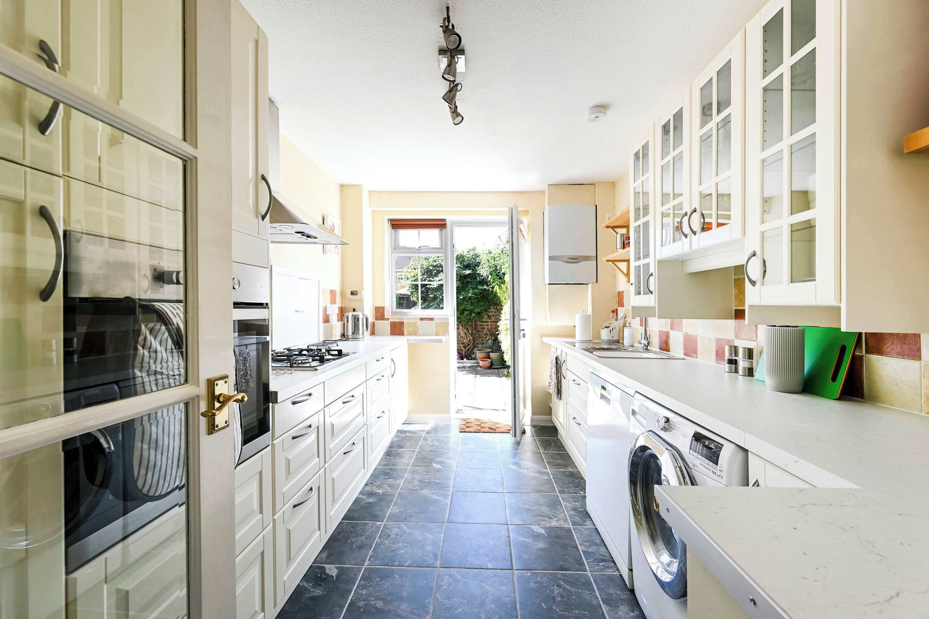 A kitchen with a washing machine, a stove, and cabinets.