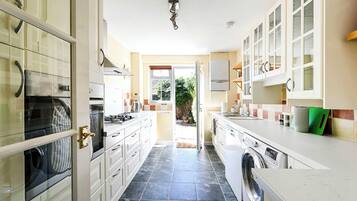 A kitchen with a washing machine, a stove, and cabinets.