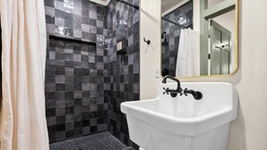 Een badkamer met een douche, een wastafel en een spiegel.