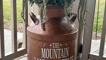 Una maceta de terracota grande con una planta suculenta y enredaderas colgantes, con la etiqueta 'The Mountain Laurel Cottage'.
