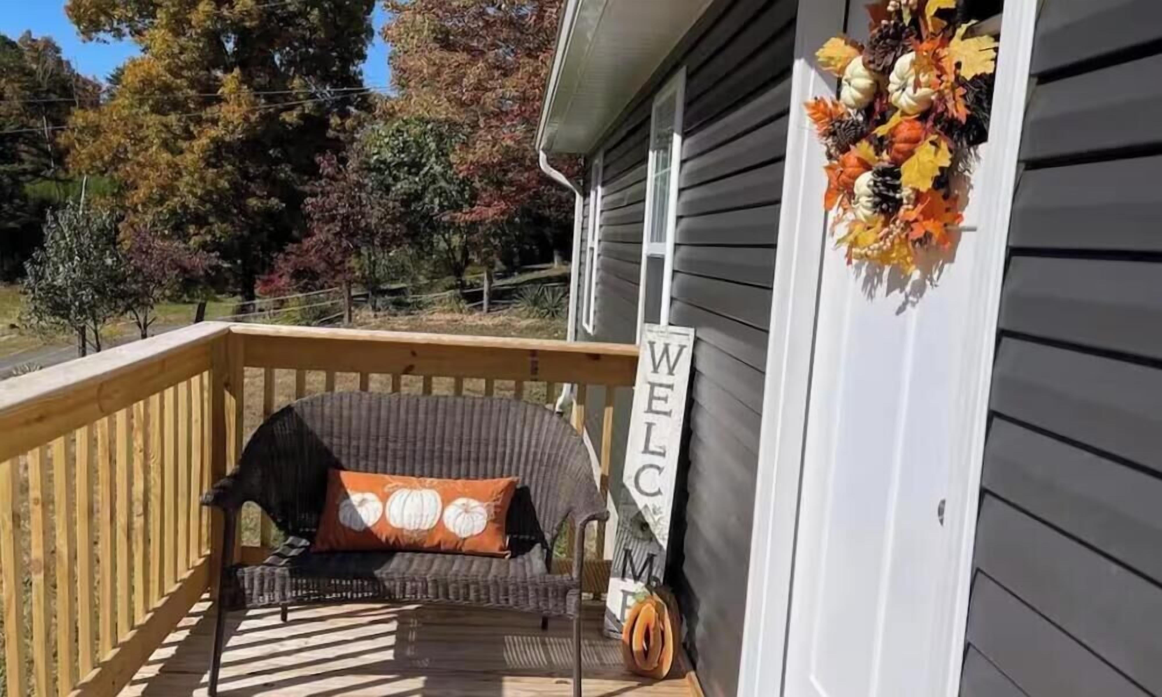 A wooden deck with a wicker chair and a welcome sign.