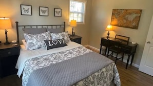 A bedroom with a bed, two bedside tables, a desk, a chair, and a window. - The Mountain Laurel Cottage Near Wildcat ATV Park. (East Bernstadt)