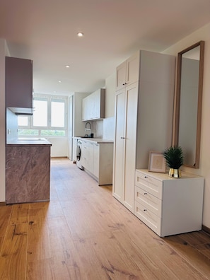 Une cuisine moderne dotée d’un plan de travail en marbre, de meubles blancs et d’un grand miroir.