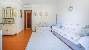 Habitació amb un sofà, un armari, una porta i una paret amb quadres.