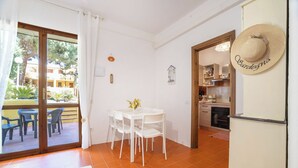 Habitació amb taula de dinar, cadires, zona de cuina i vista a un edifici a l'exterior.