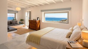 Un dormitorio con cama, cómoda, mesita de noche, lámpara y vista al mar.