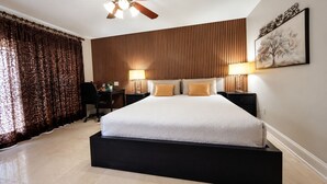 Ein Schlafzimmer mit Bett, Schreibtisch, Stuhl, Deckenventilator und Wandlampen.