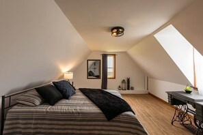 Un dormitorio con cama, escritorio, ventana y lámpara en el techo.