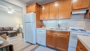 A kitchen with wooden cabinets, a white refrigerator, a dishwasher, and a stove. - Beachfront Cottage Sleeps up to 4 Unit A (Indian Rocks Beach)