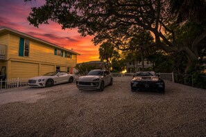 Drei Luxuswagen parken vor einem gelben Gebäude mit weißem Zaun.