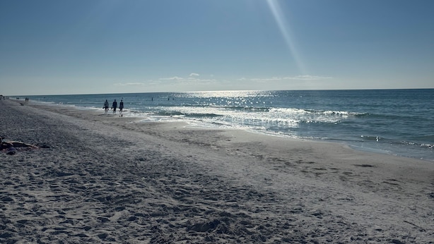 A beach with a clear sky, sun shining, and people walking along the shore. - Beachfront Cottage Sleeps up to 4 Unit A (Indian Rocks Beach)