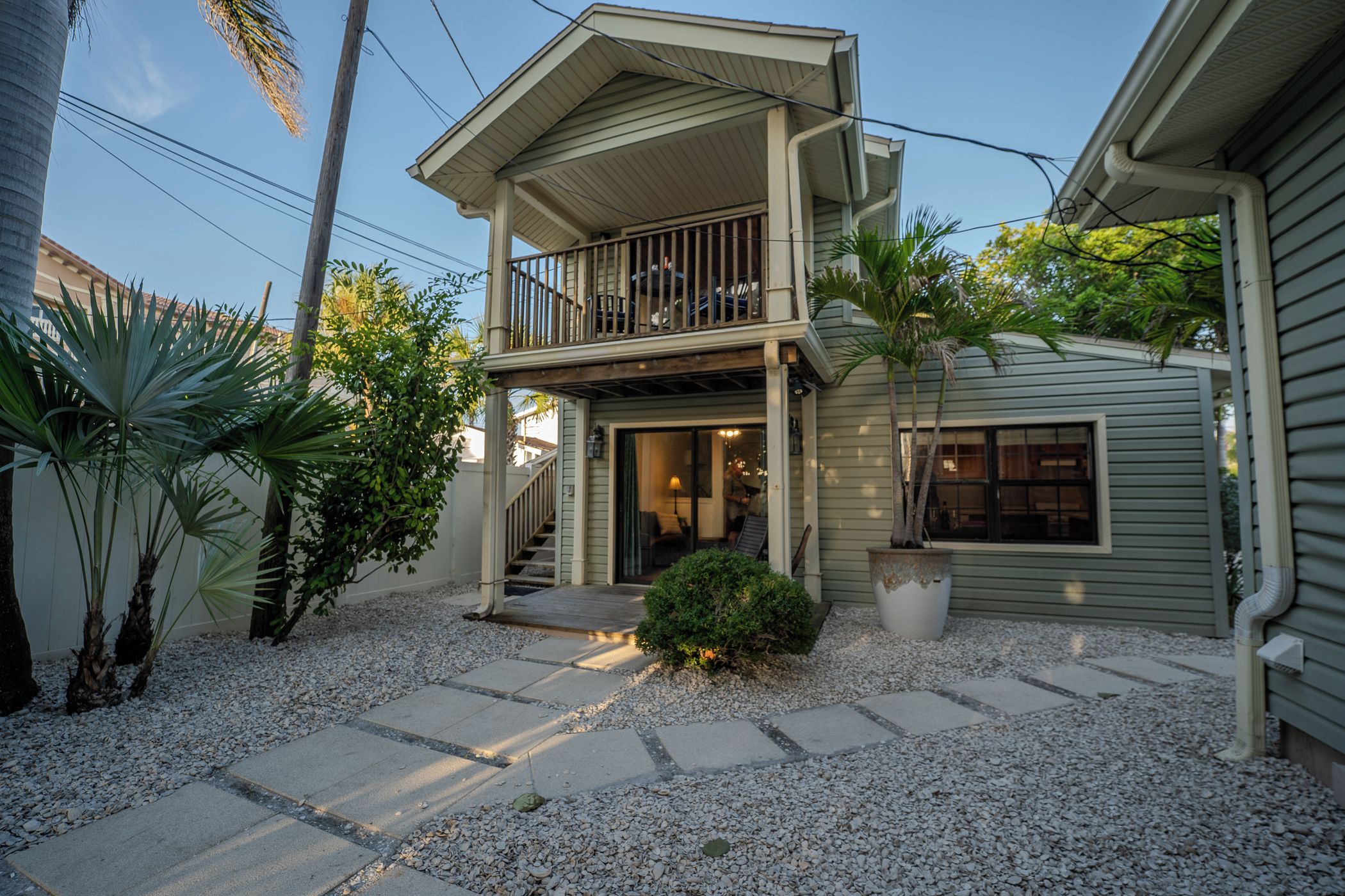 A two-story house with a balcony, a covered porch, and a gravel driveway.