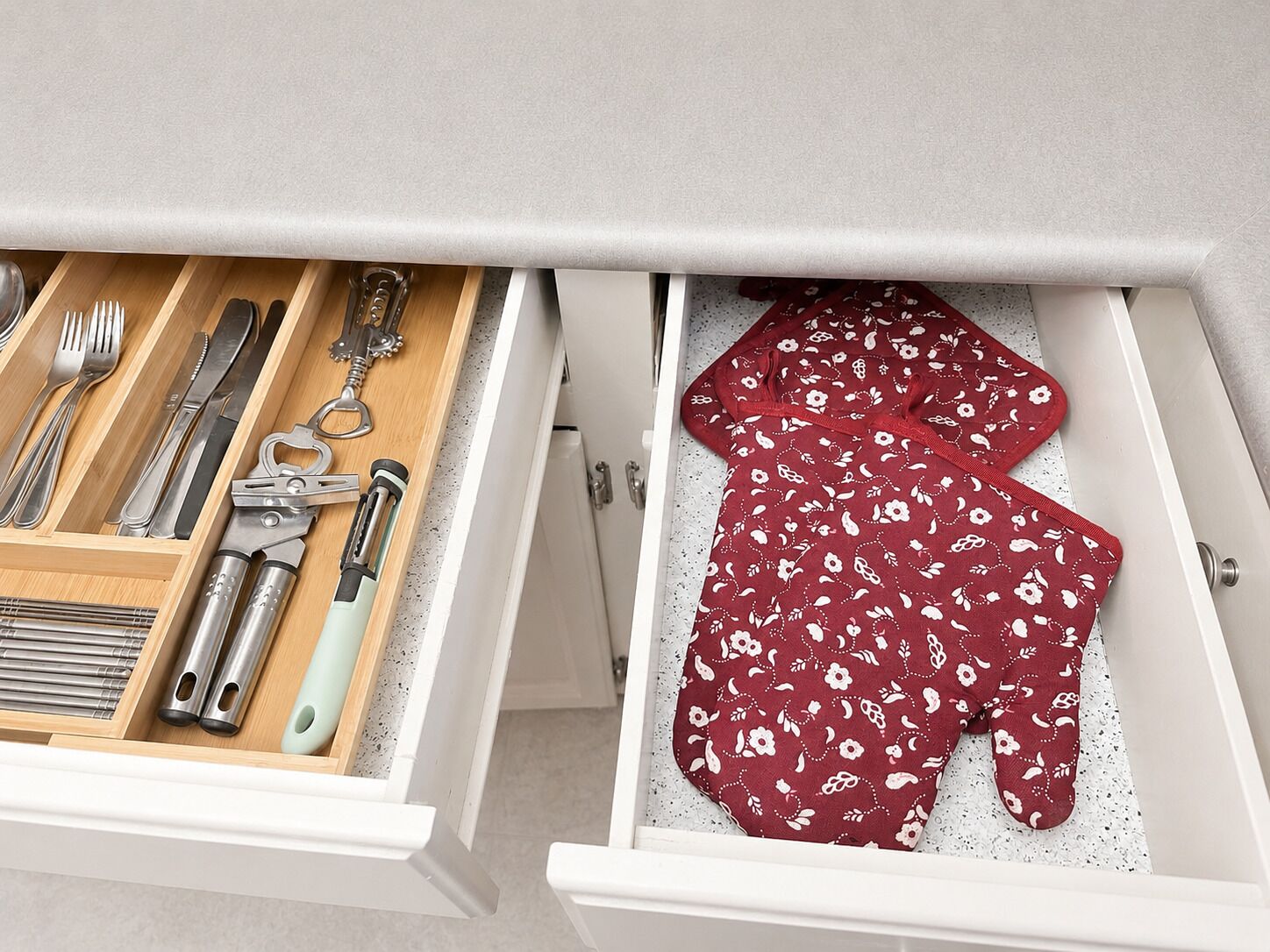A drawer with utensils and a red patterned cloth.