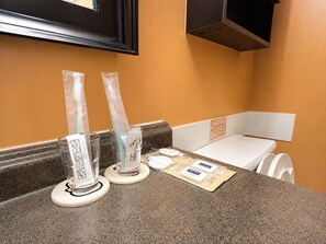 Un bagno con un lavabo, due dispenser in vetro, un lavandino bianco e un portasciugamani.