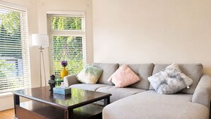 A living room with a sofa, a coffee table, a lamp, and a vase with flowers.
