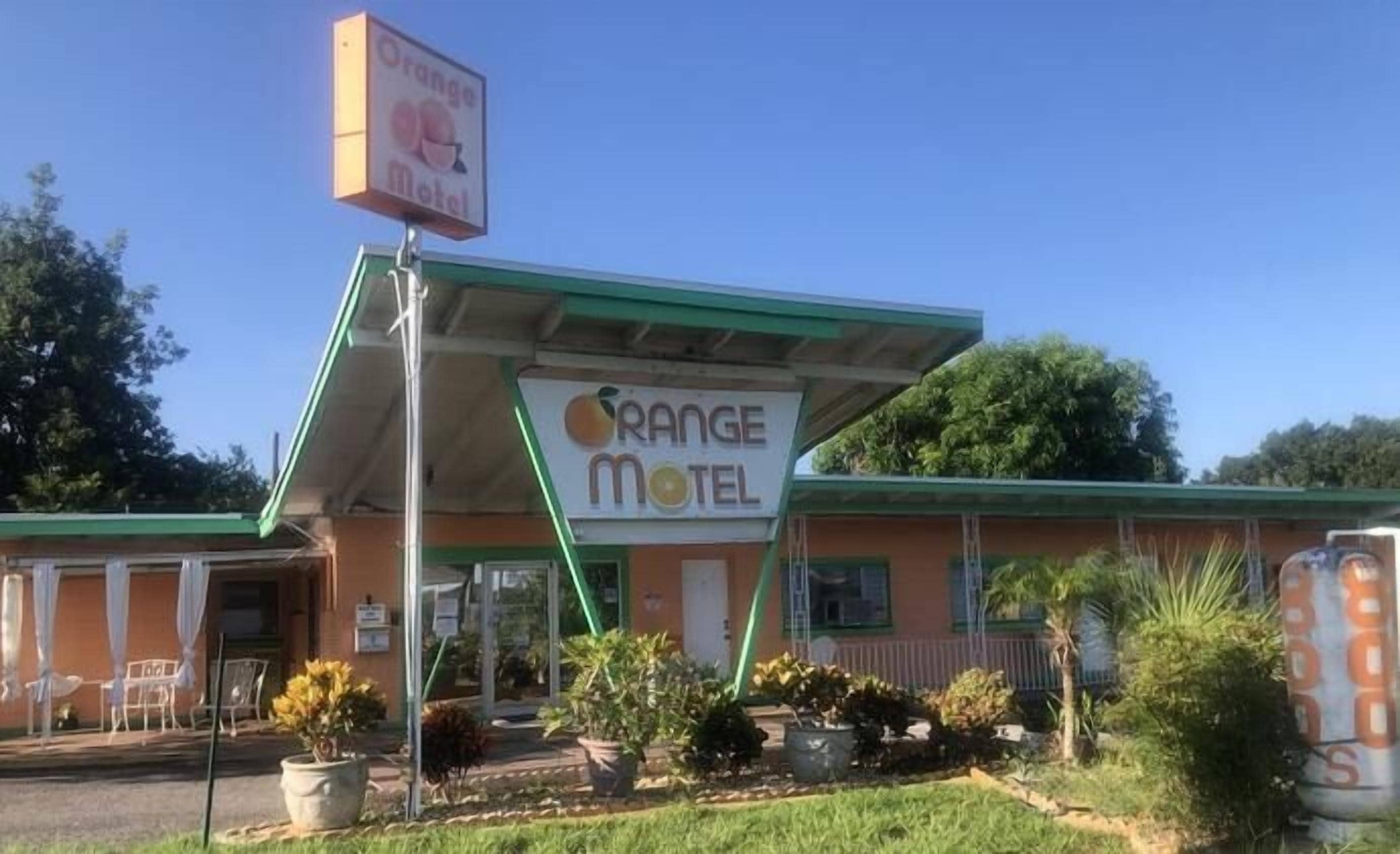 A motel with a green roof and a sign that reads 'Orange Motel.'