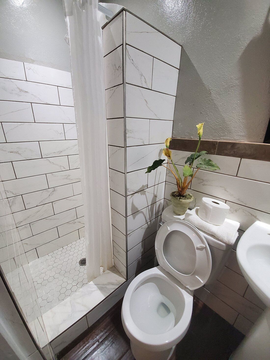 A bathroom with a shower, toilet, bidet, and sink.