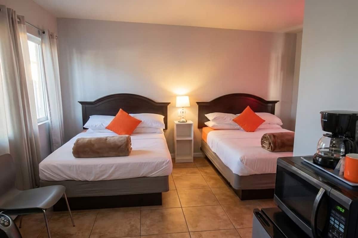 Ein Hotelzimmer mit zwei Betten, einem Sessel, einer Kaffeemaschine und einer Mikrowelle.