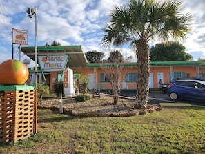 Un motel con un letrero que dice 'Orange Motel' y una esfera naranja grande en un poste.