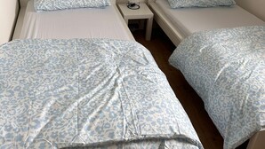 Zwei Einzelbetten mit passenden Kopfteilen und Fußteilen, ein kleiner Nachttisch mit Lampe und ein Holzboden.