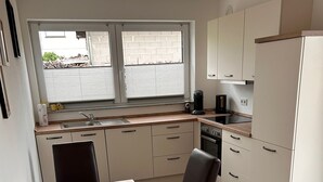 Eine moderne Küche mit Esstisch, Stühlen und einem Fenster mit Jalousien.