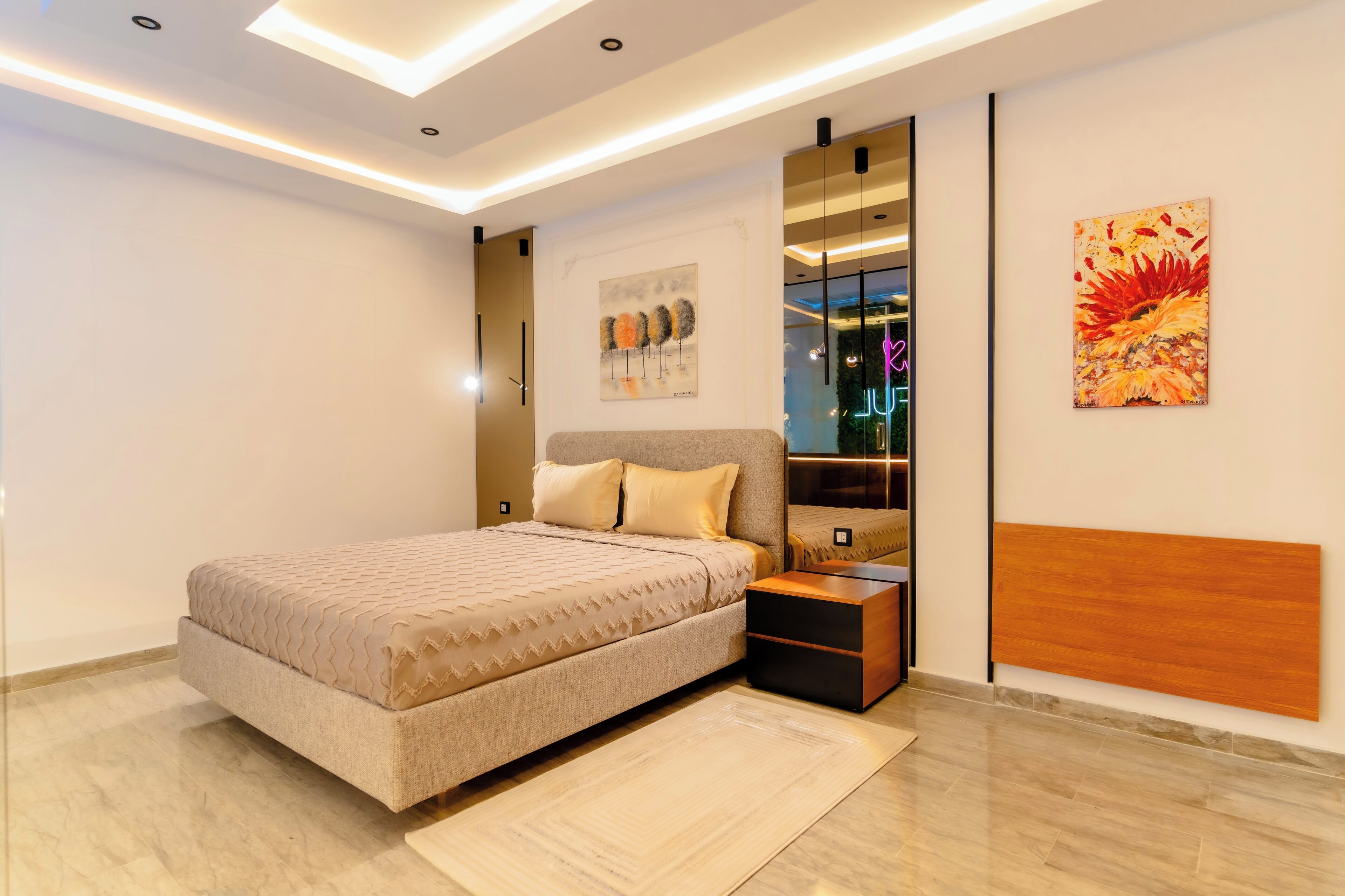 Un dormitorio moderno con cama, mesitas de noche, un espejo y obras de arte en las paredes.