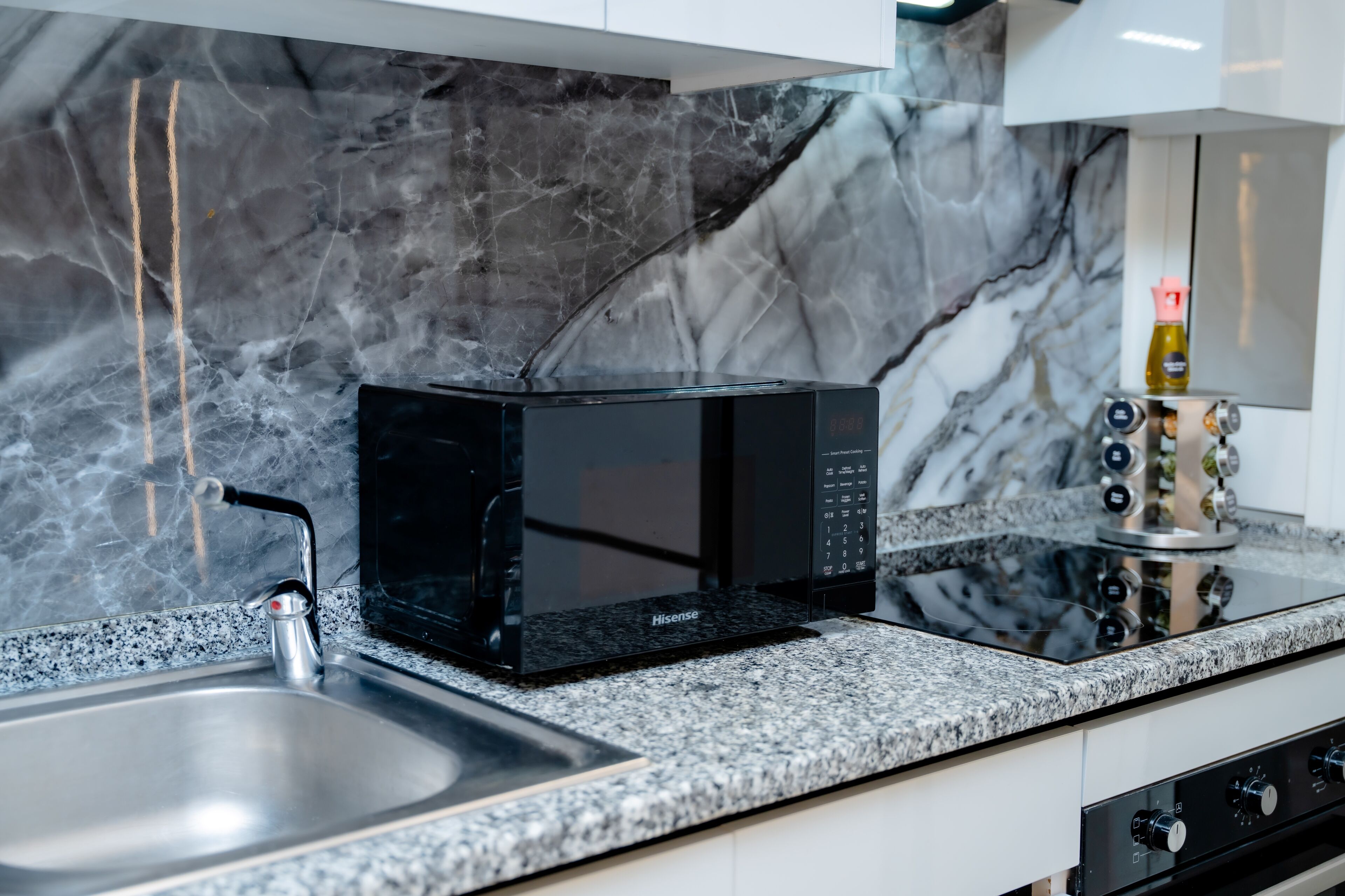 A kitchen with a black microwave, stainless steel sink, and a gas stove.