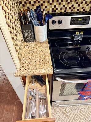 A kitchen with a granite countertop, stainless steel appliances, and a drawer organizer with utensils. - Thunder Up Loft Garage Apt 10 min to Downtown (Oklahoma City)