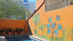 Une piscine dont le mur adjacent est décoré d’une fresque représentant des plantes tropicales.