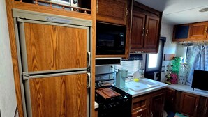 Une cuisine compacte avec des meubles en bois, un four à micro-ondes, une cuisinière et un évier.