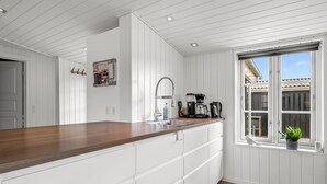 Una cucina moderna con mobili bianchi, un piano di lavoro in legno, un lavello incassato e una finestra con vista.