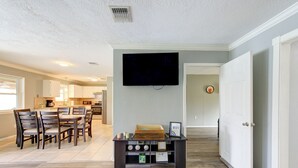 A living room with a flat-screen TV, a dining area with wooden chairs and a table, and a kitchen in the background. - Private Pool Paradise in La Porte. Family & Work Stays Welcome (La Porte)