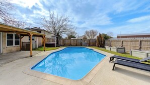 A rectangular swimming pool with a wooden deck and lounge chairs, surrounded by a wooden fence and a house. - Private Pool Paradise in La Porte. Family & Work Stays Welcome (La Porte)