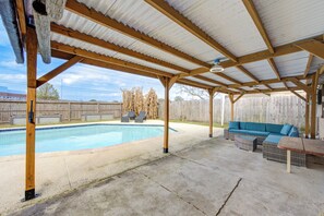 Un espacio al aire libre cubierto con piscina, mobiliario de madera y valla de madera.